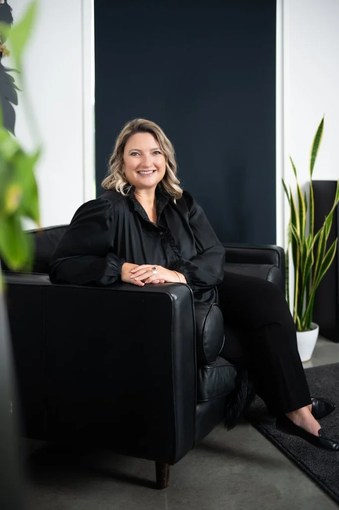 Vicki smiling in a black leather armchair